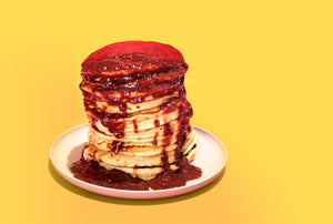 chia smash over a stack of pancakes against a bold yellow background